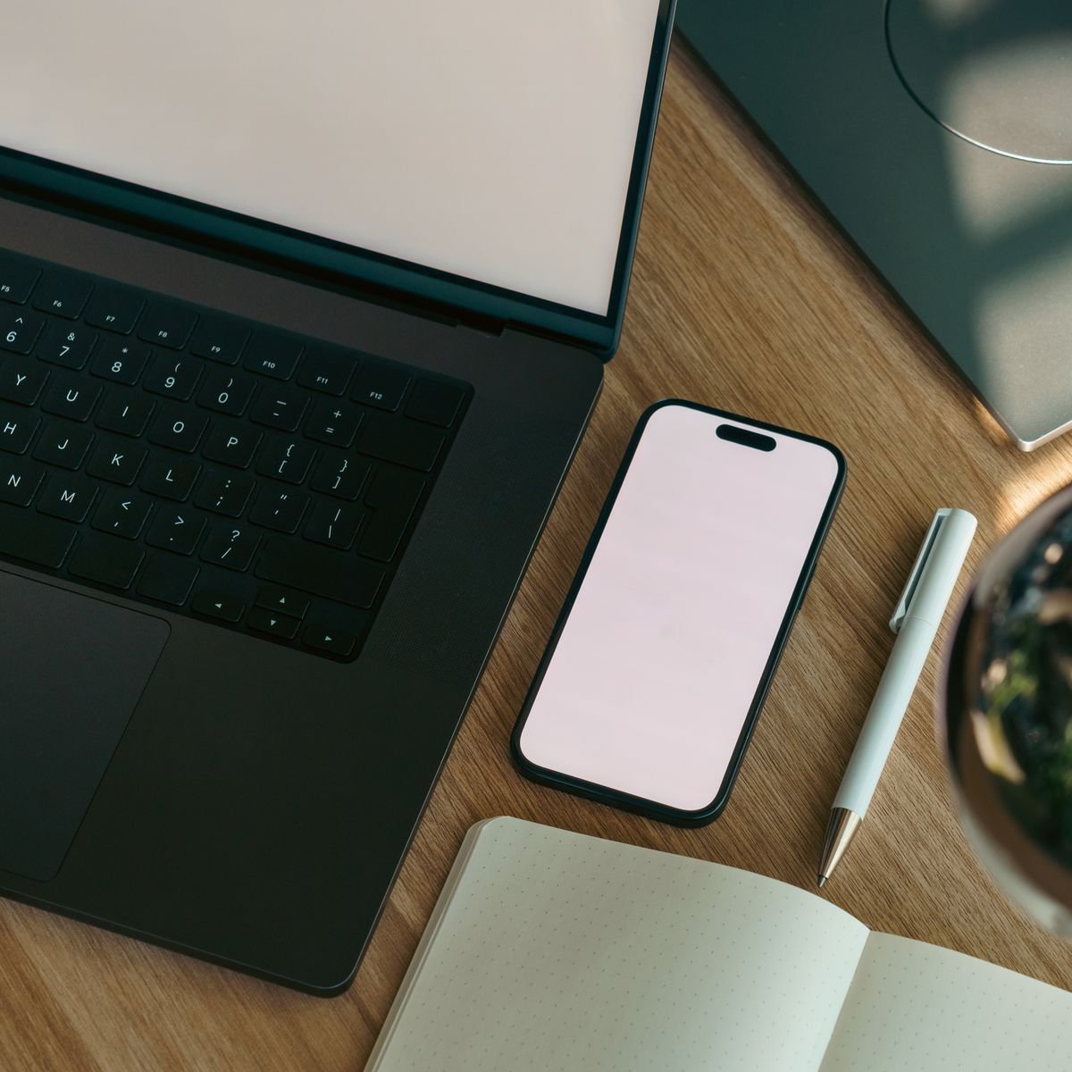 Laptop, smartphone, and notebook arranged on a desk